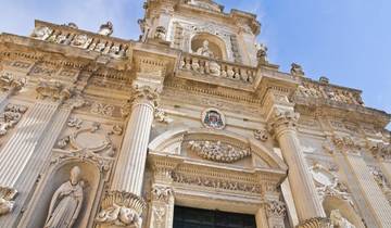 A scenic rural road in Puglia winding through olive groves and historic stone walls.