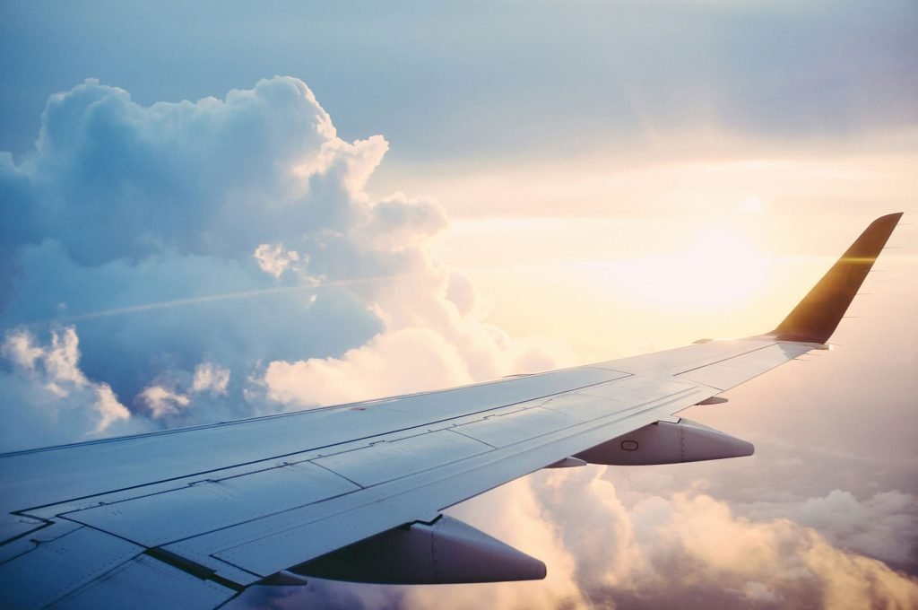A view of an airplane wing through a cabin window high above the clouds.