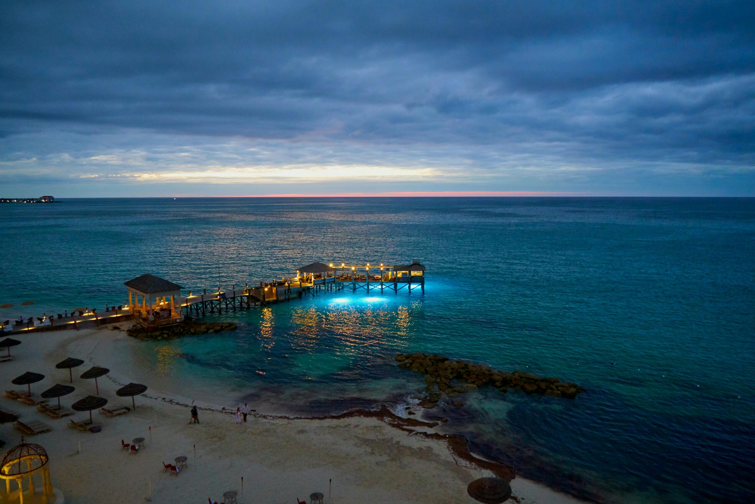 Luxury overwater bungalows reflecting on calm turquoise waters during a soft dawn glow.
