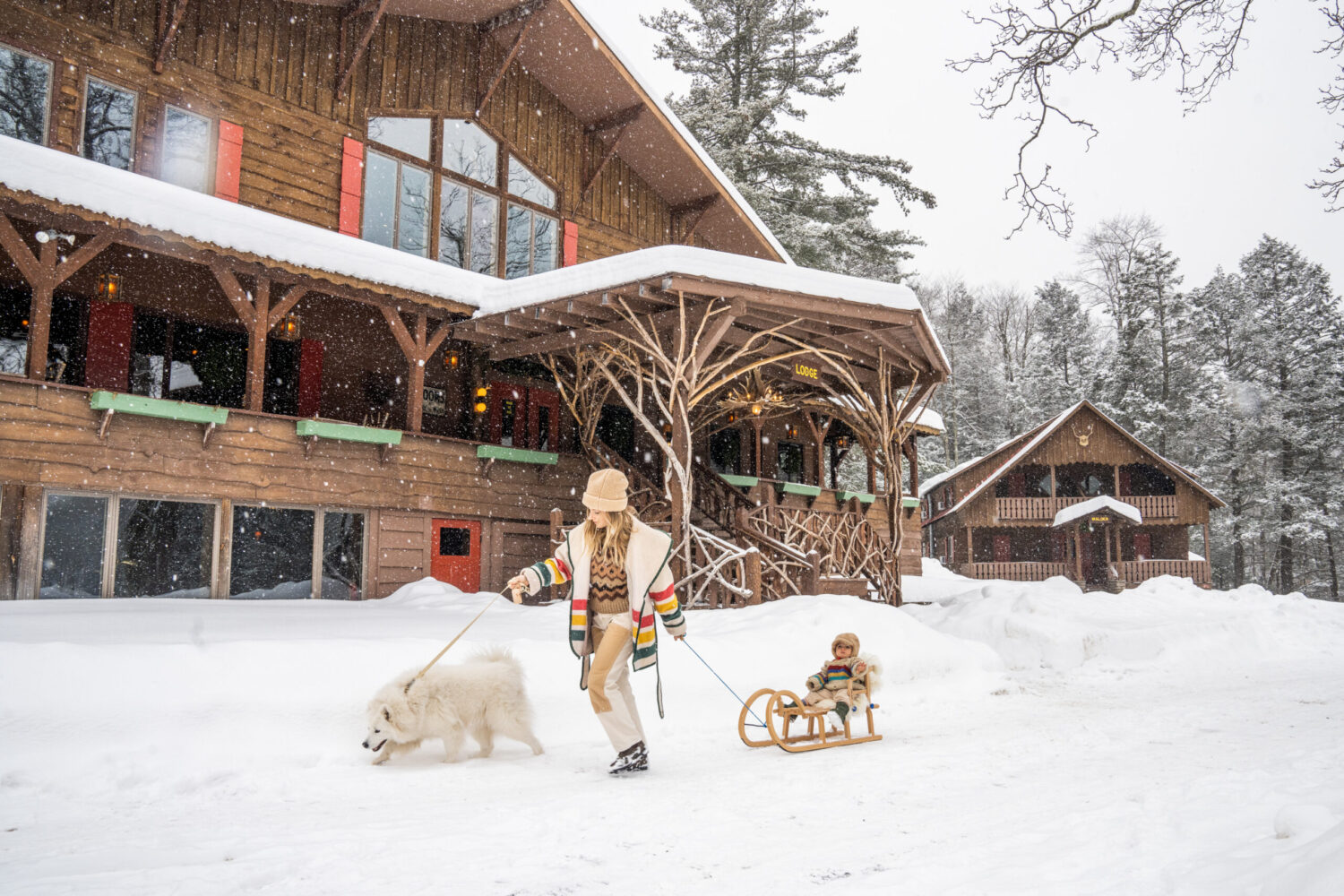 The snow-covered exterior and wooded grounds of the Urban Cowboy Lodge in winter.
