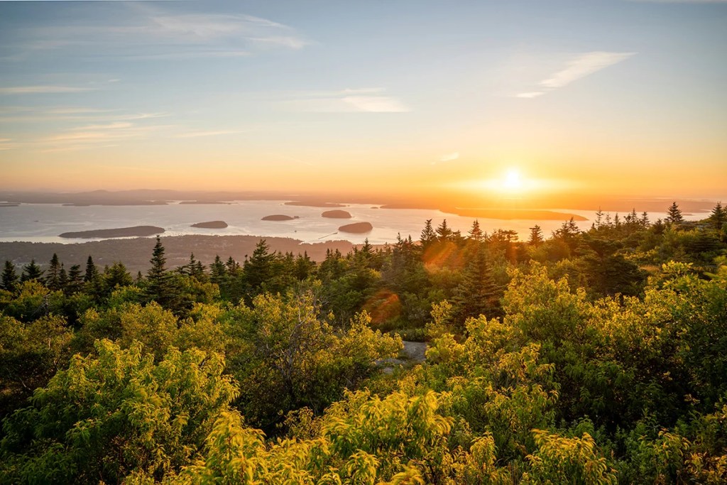 The first rays of sunrise hitting the rocky summit of Cadillac Mountain in Acadia National Park.
