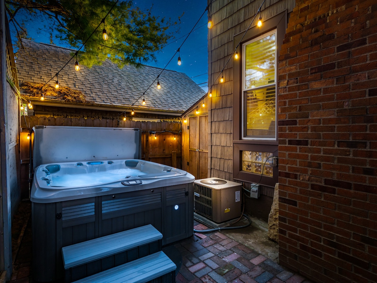 A steaming outdoor hot tub surrounded by string lights and a wooden deck.