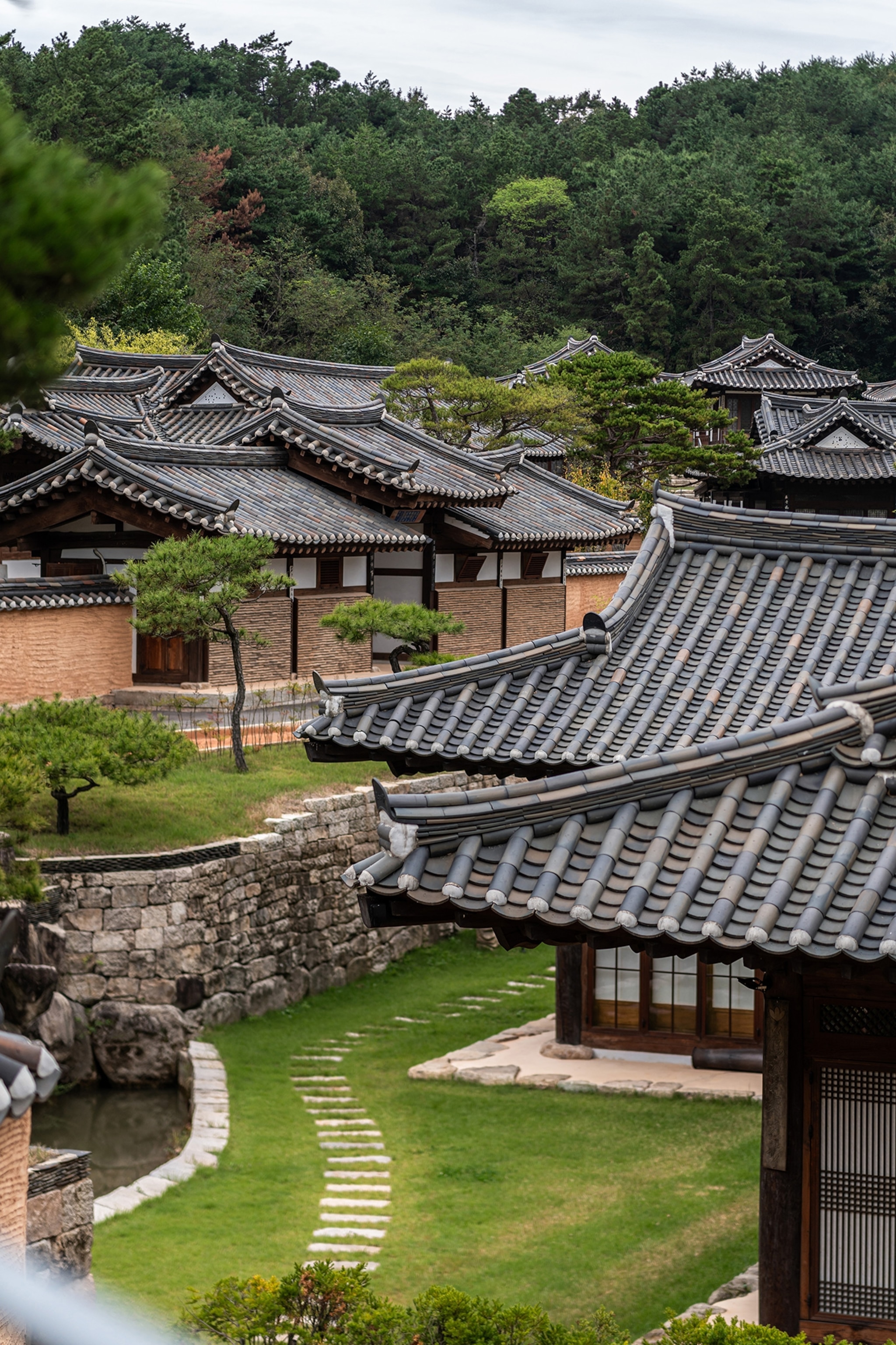 A wide shot of dark-tiled traditional Korean roofs with mountains in the distance.