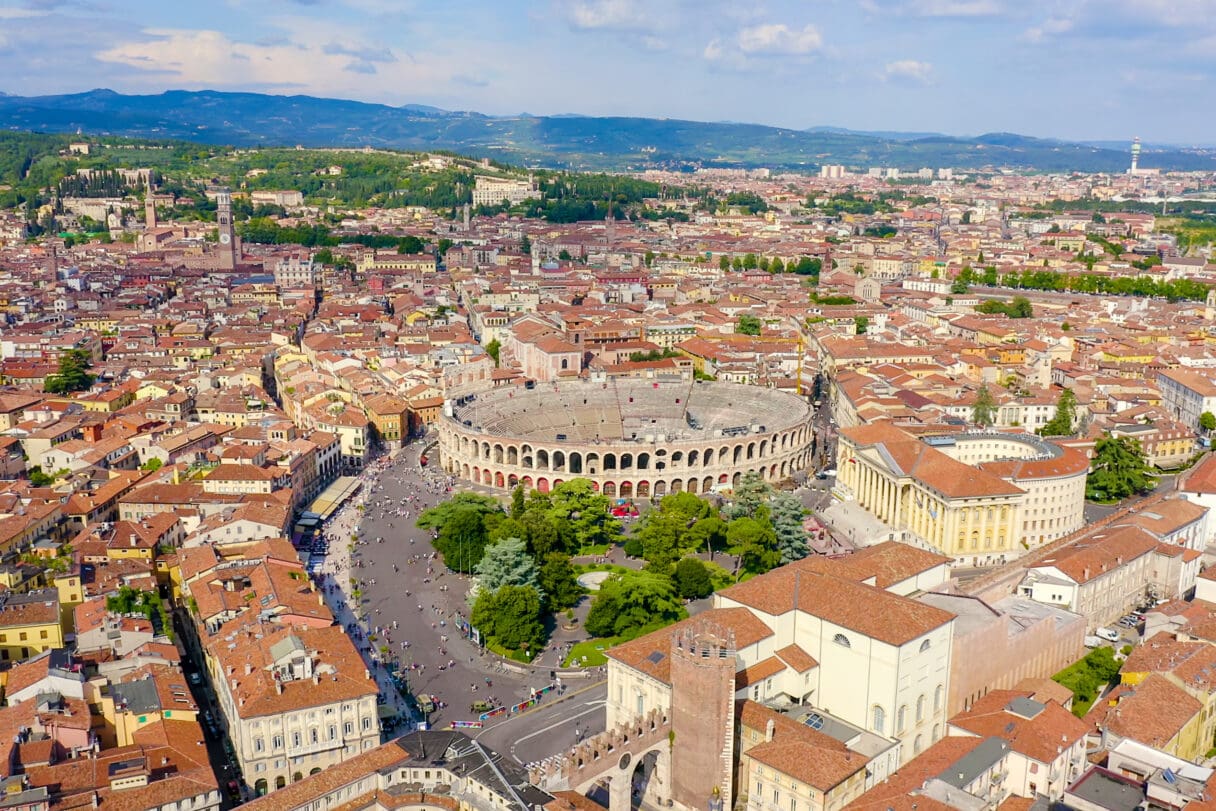 The well-preserved exterior of the ancient Roman amphitheatre, Arena di Verona, under a bright sky.