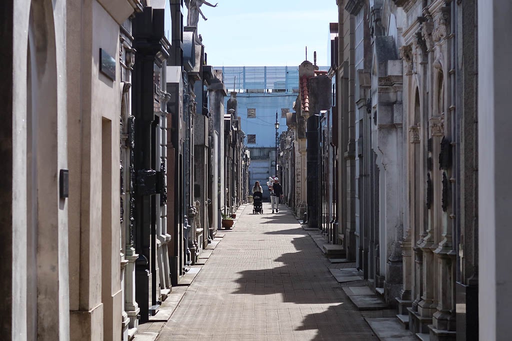 Ornate marble statues and crypts at the Recoleta Cemetery under dramatic shadows.
