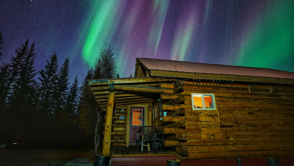 A small wooden cabin in North Pole, Alaska, with a light dusting of snow.