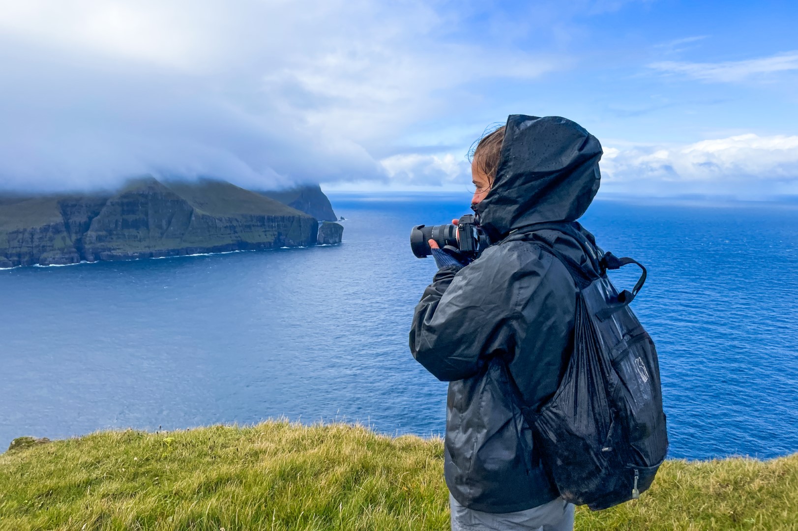 A peaceful coastal village in the Faroe Islands with green hills and calm water.