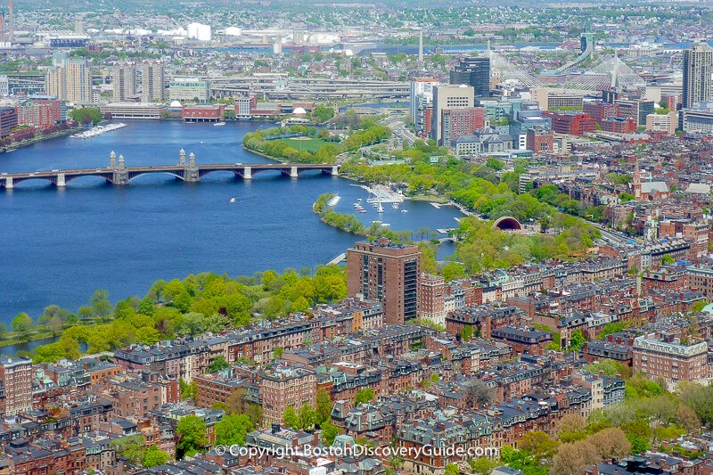 High-angle aerial view looking down at the Charles River and Boston city grid from a skyscraper.