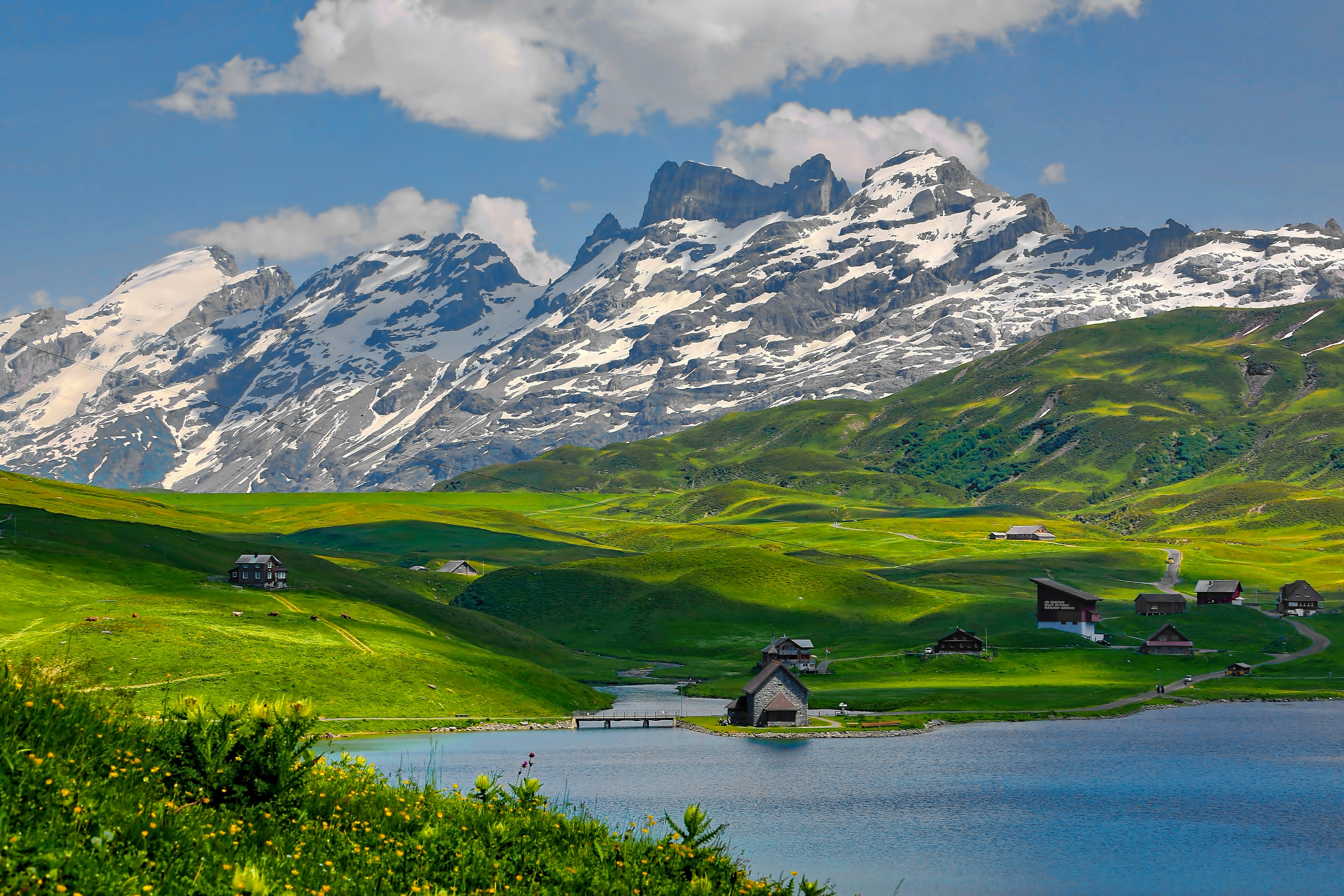 The incredibly bright turquoise water of Cracker Lake at the base of a steep grey mountain.