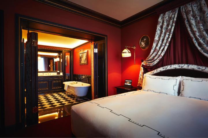 Opulent Parisian-style hotel room with red velvet and classic European decor