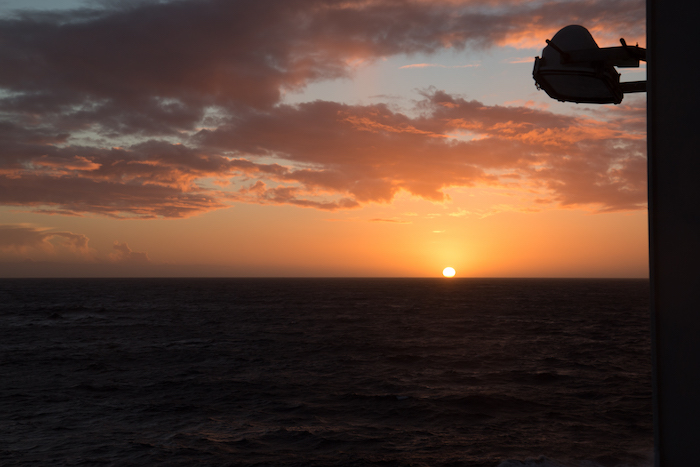 A side profile view of a large multi-deck luxury cruise ship sailing across the open sea.