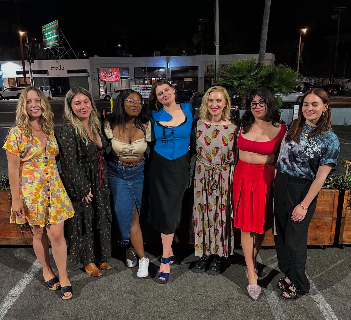 Diverse group of people gathering outside a lesbian bar at night.