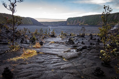 Dramatic dark volcanic cliffs meeting the blue ocean waves in Hawaii Volcanoes National Park.