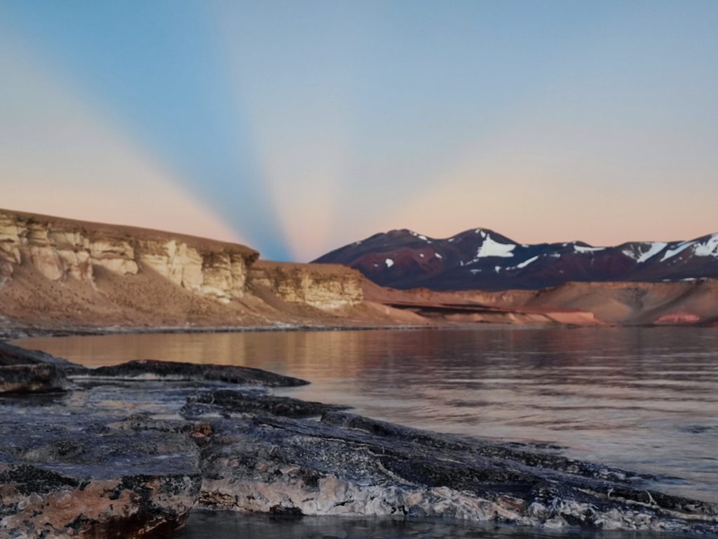 Yellow and orange tents set up at a base camp on a rocky volcanic slope.