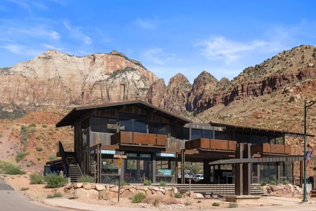 A modern luxury home built into red rock formations with a desert landscape background.