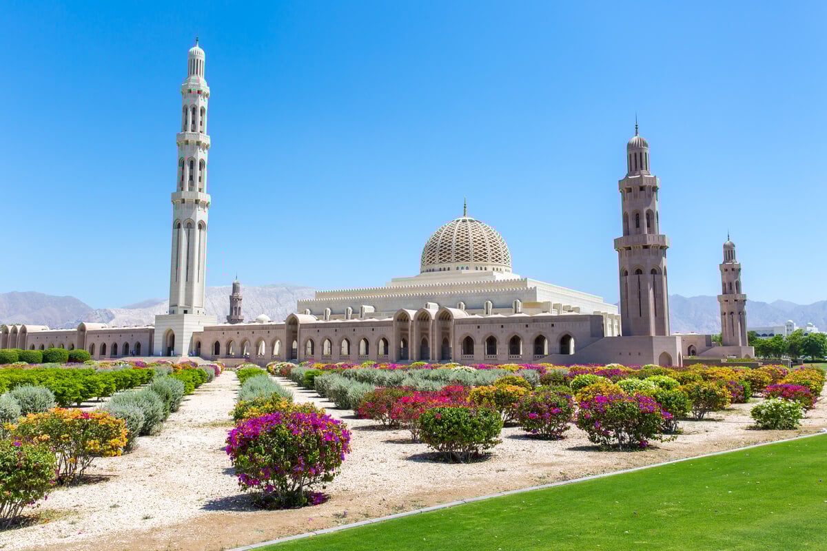 The grand white marble exterior and domes of the Sultan Qaboos Grand Mosque.