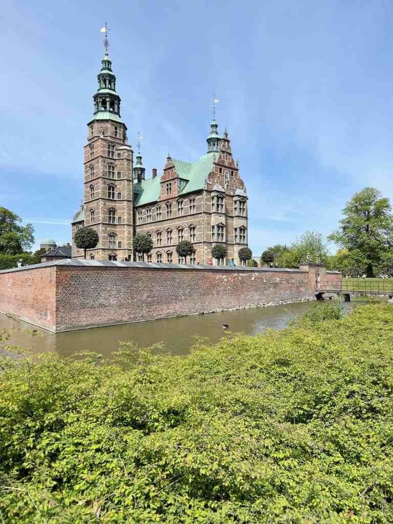 The red-brick Rosenborg Castle reflected in the water of its surrounding moat.