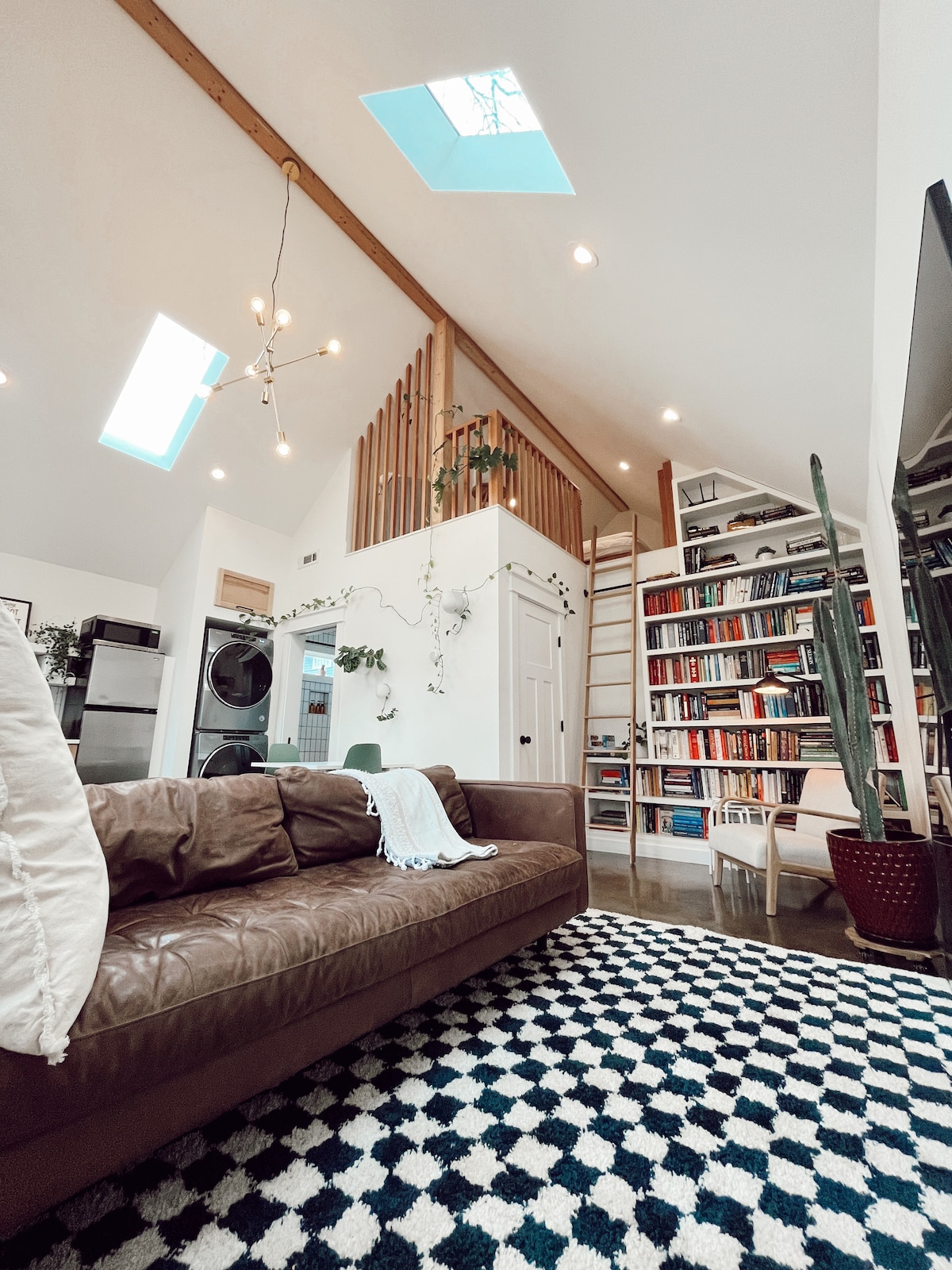 Interior view of a lofted tiny home featuring modern furniture and high ceilings.
