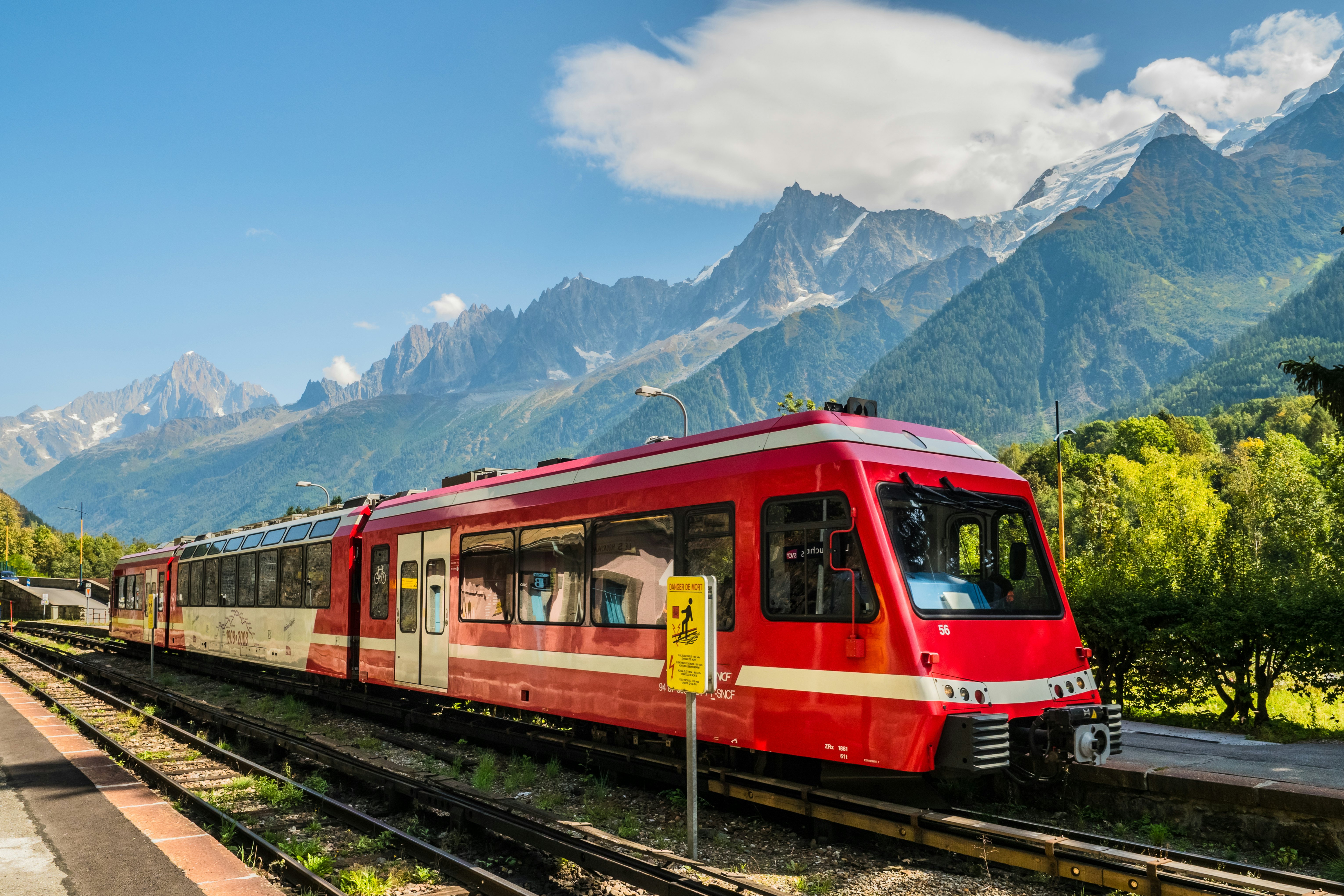A red mountain train winding through a snow-dusted Alpine valley.