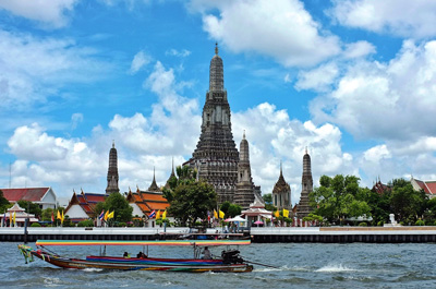The towering prang of Wat Arun reflected along the banks of the Chao Phraya River.