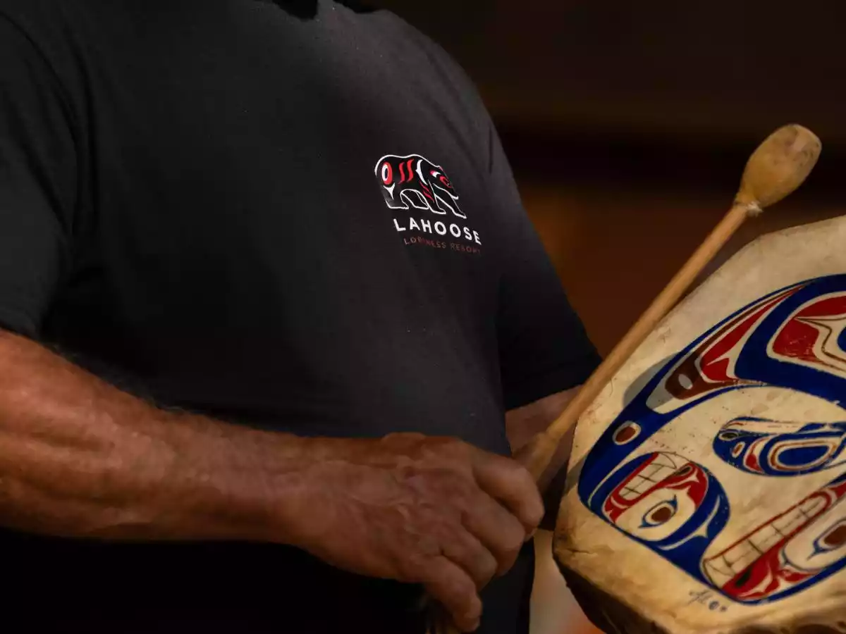 Indigenous hosts leading a traditional demonstration and storytelling session indoors at a wilderness lodge.