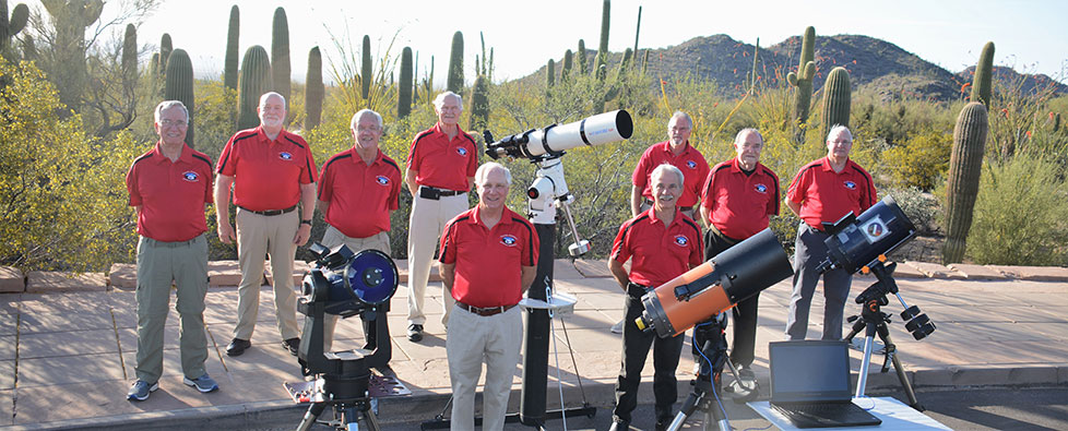 A group of people gathered outdoors at night for a guided stargazing session in the desert.