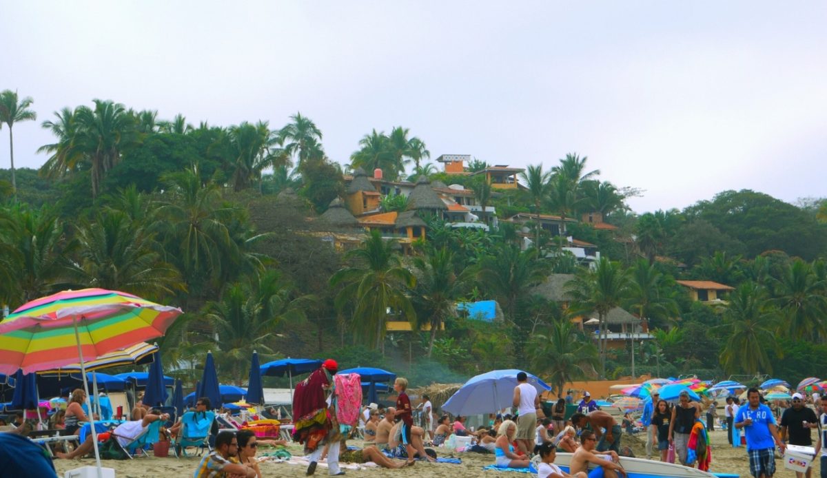 Vibrant beach scene in Sayulita with colorful umbrellas and palm trees.