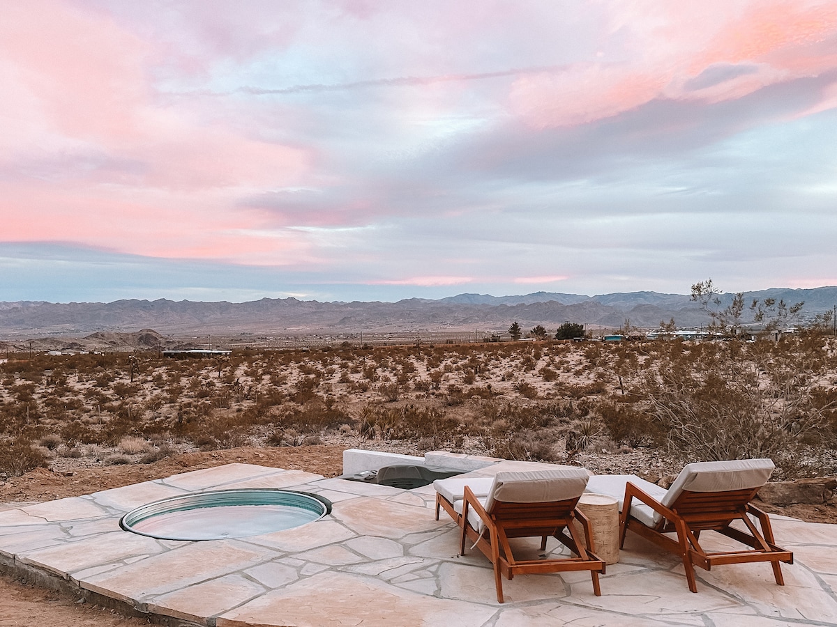 An outdoor soaking tub on a wooden deck with a view of a vast desert valley.
