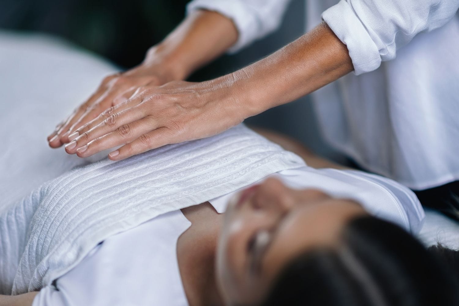 A person receiving a Reiki energy healing treatment in a peaceful wellness setting.