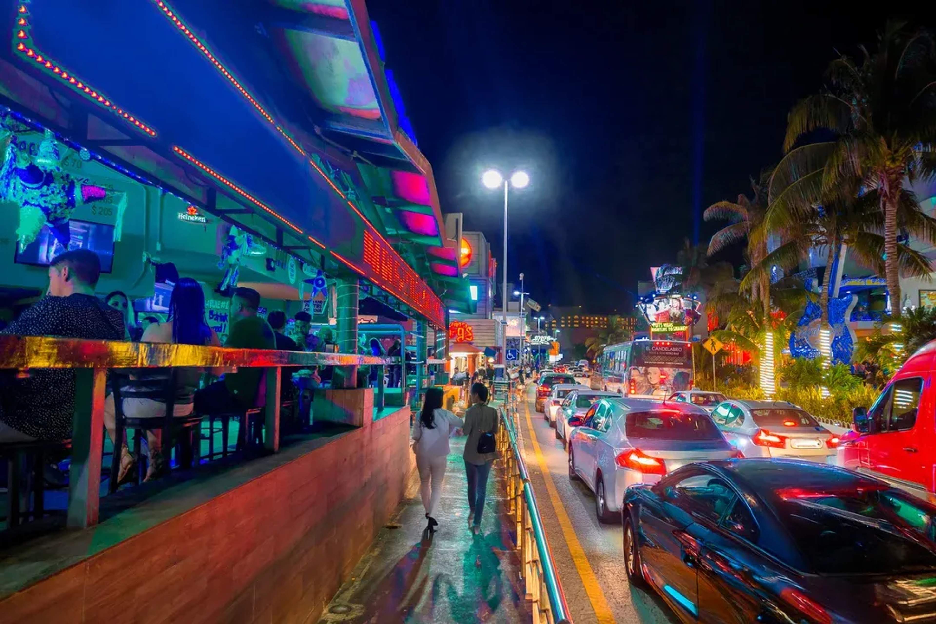 Bright neon lights and busy traffic in the nightlife district of the Cancun Hotel Zone.