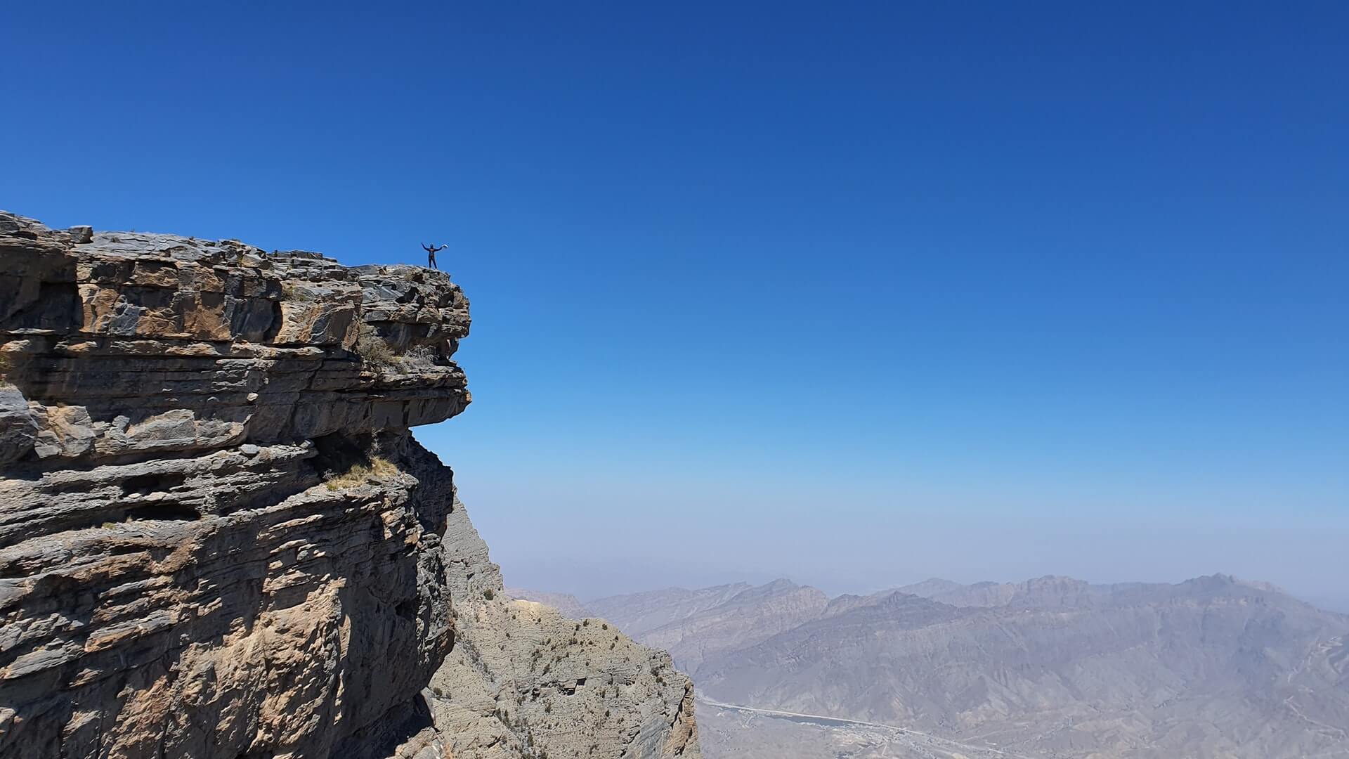 An expansive aerial view looking down into the massive canyons from a Jebel Shams lookout.