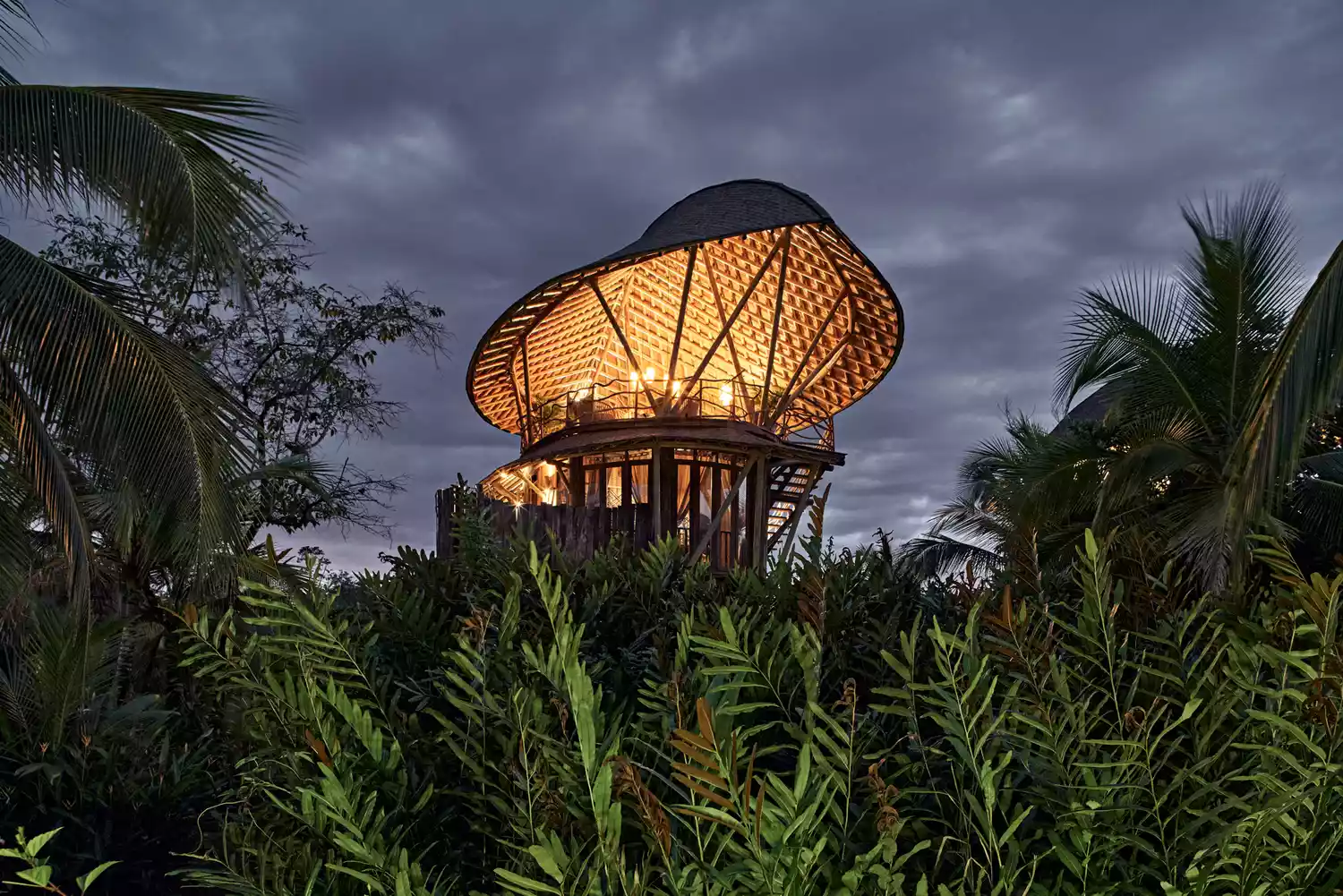 A luxury treehouse structure at Nayara Bocas del Toro illuminated at night.