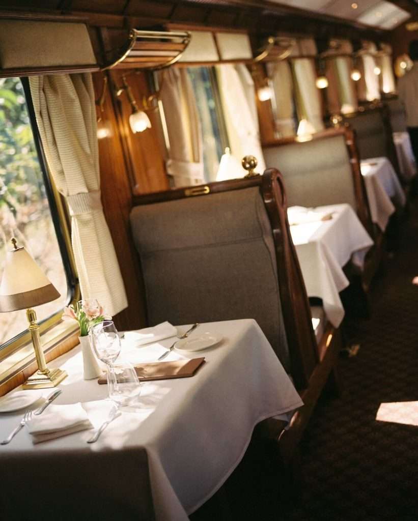 The interior of the Belmond Hiram Bingham luxury train car with polished wood and golden accents.