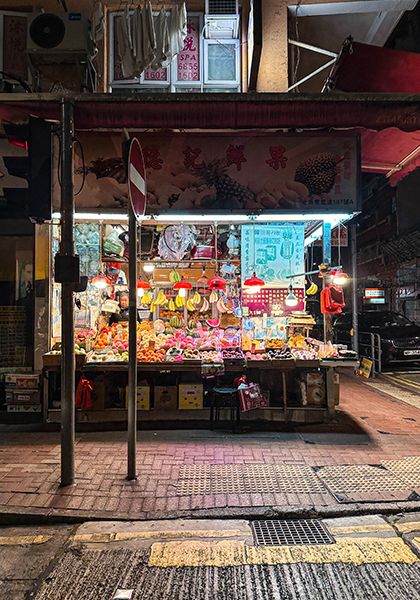A street level view of Hong Kong at night featuring glowing neon signs and busy traffic.