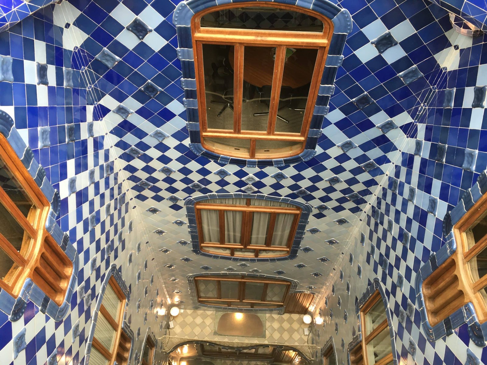 Blue-tiled interior courtyard of Casa Batlló with organic wooden window frames.