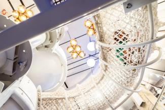 A massive three-story climbing structure and slide inside a museum.