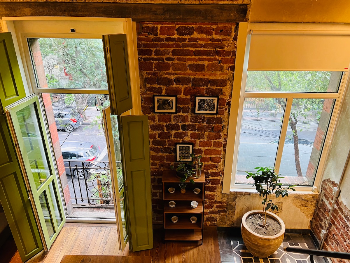 A character loft with large windows and distinctive green shutters in a 1920s building.
