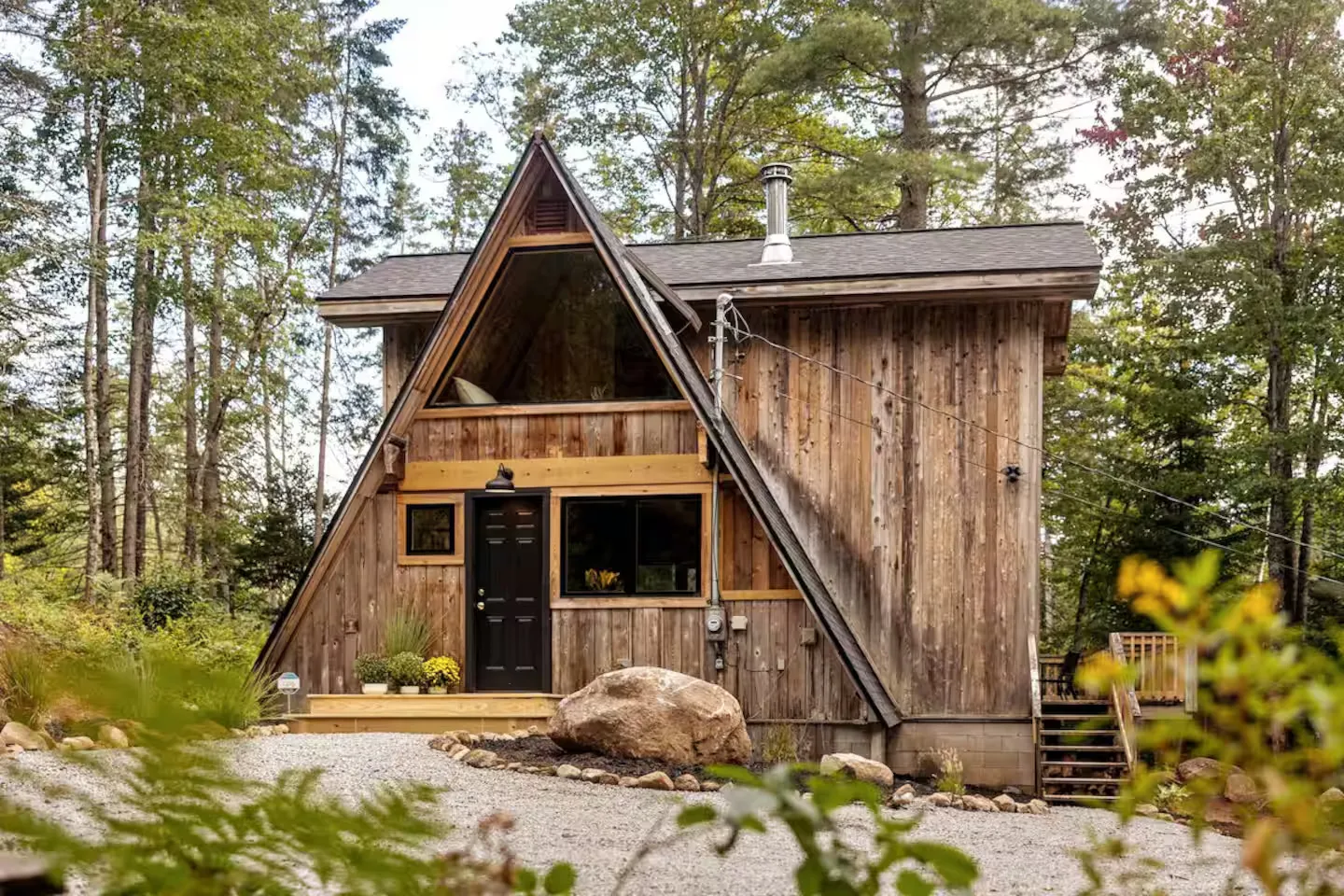 A classic A-frame cabin surrounded by deep snow and bare winter trees in the Adirondacks.