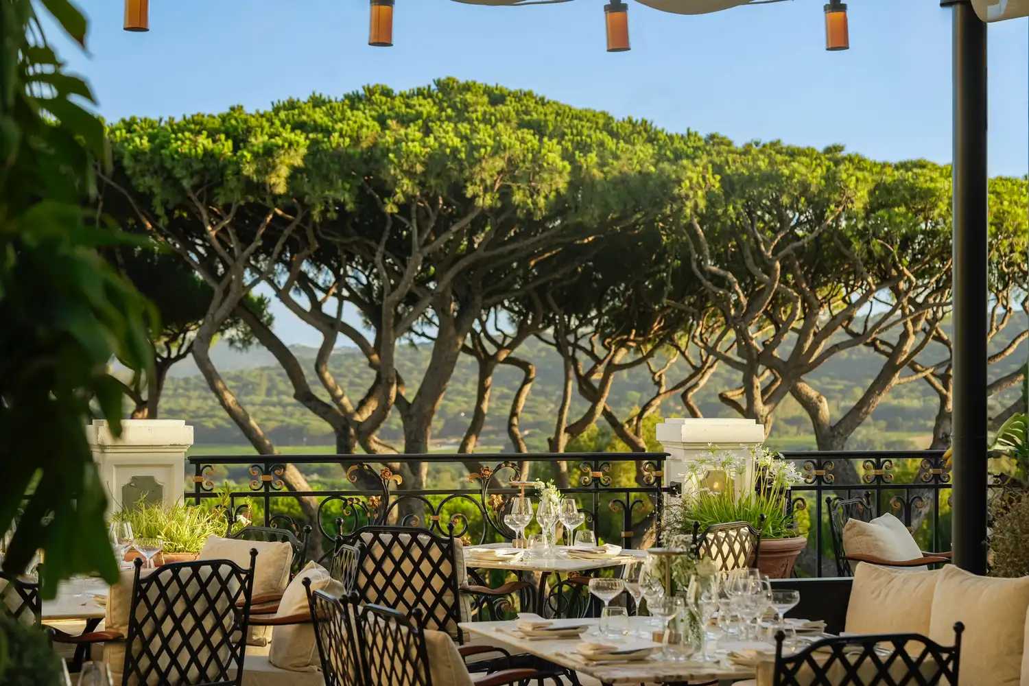 An outdoor dining terrace with set tables overlooking the scenic Saint-Tropez countryside.