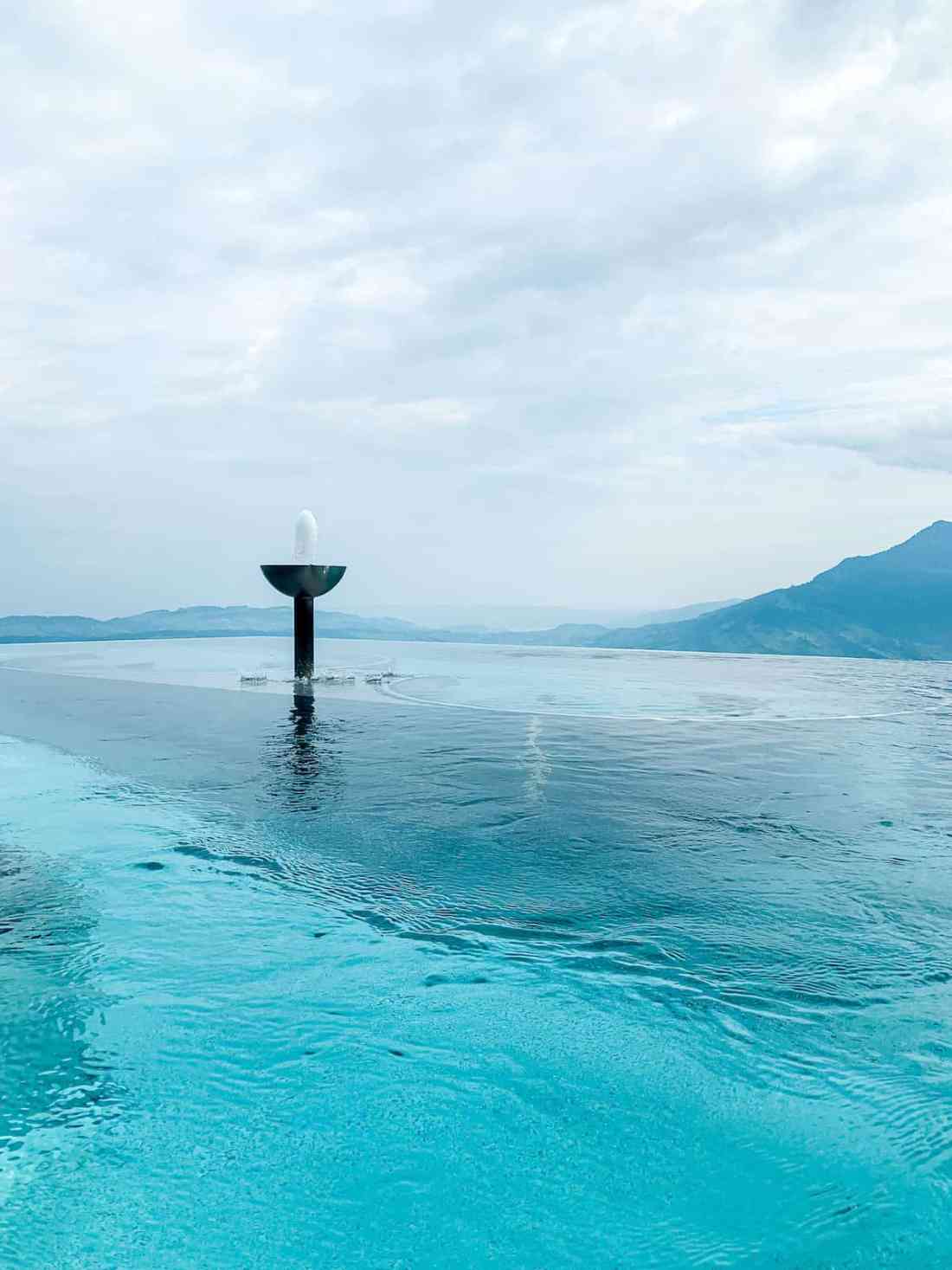 An outdoor infinity pool overlooking a valley and mountains in Switzerland.