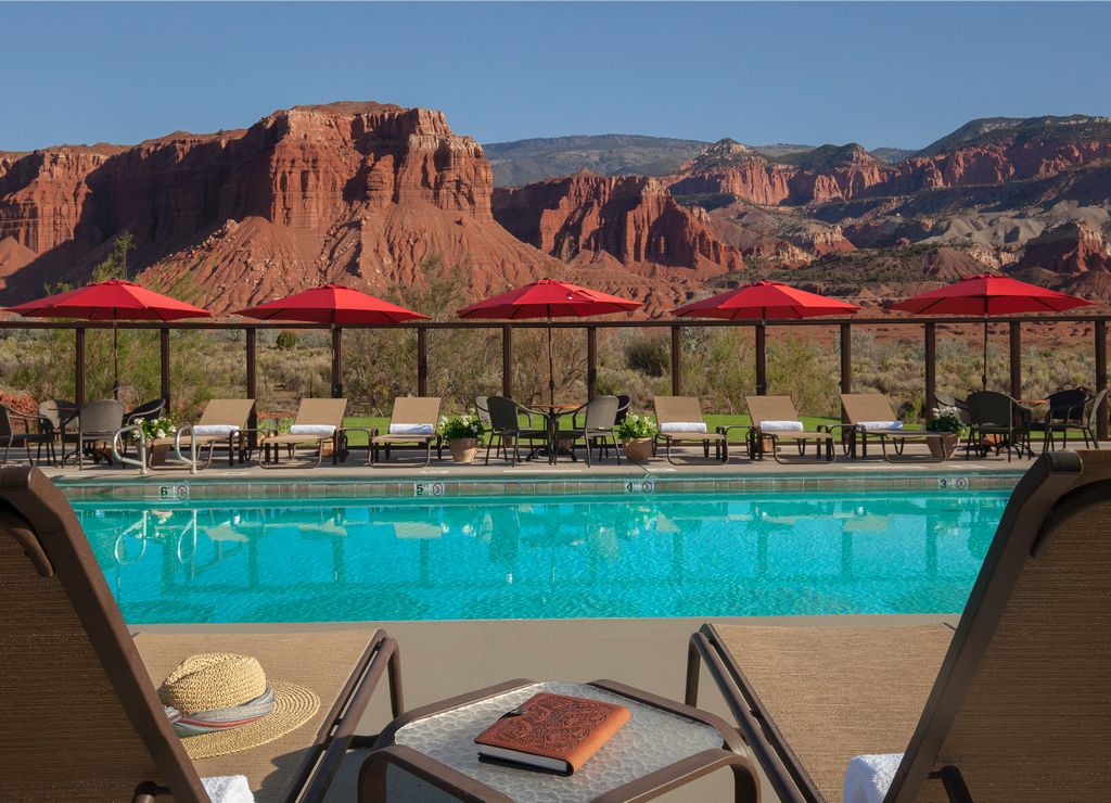 Luxury glamping teepees at Capitol Reef Resort positioned near towering red rock cliffs.