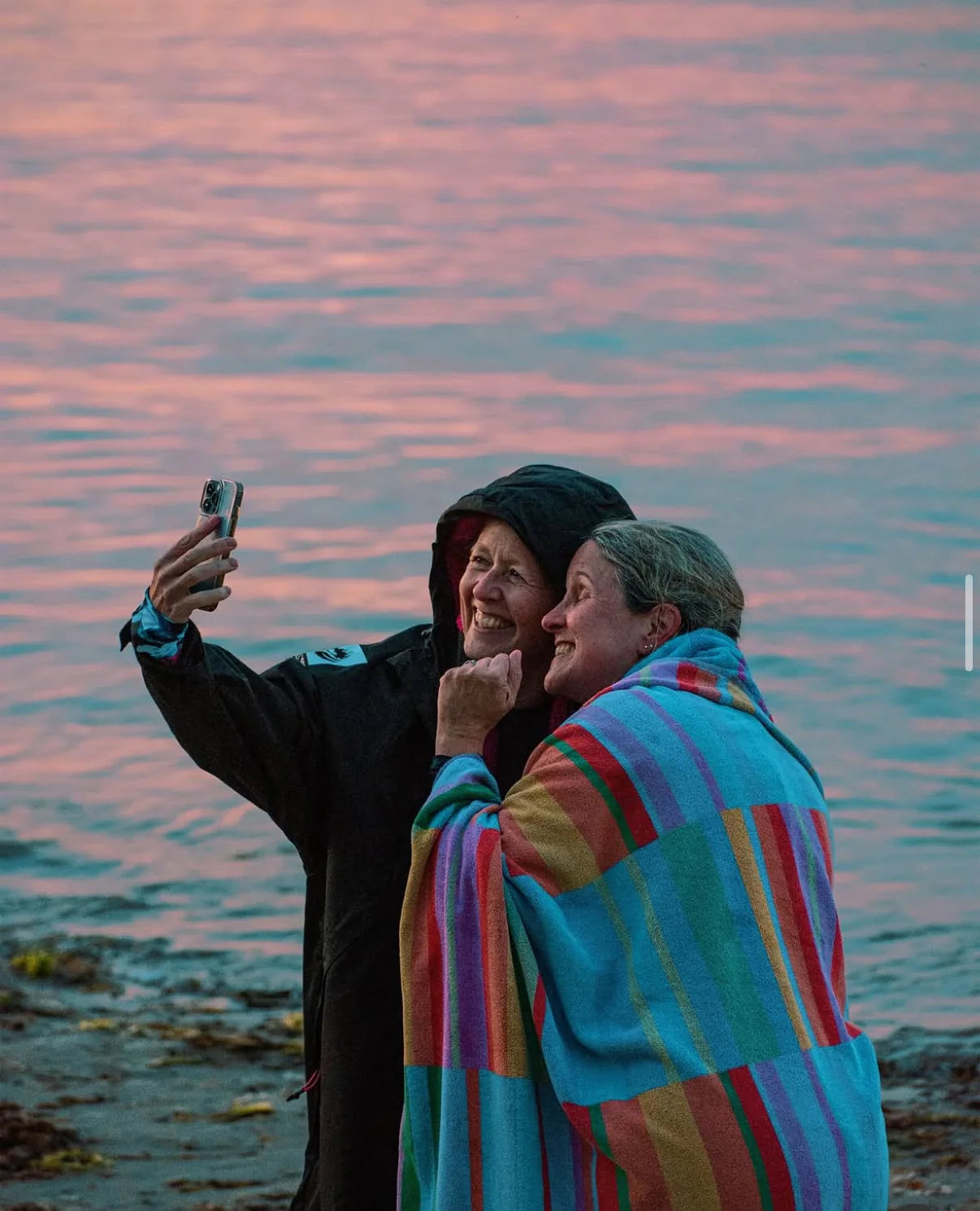 Several swimmers wearing bright neon swim caps participating in an open water event along a rocky coastline.