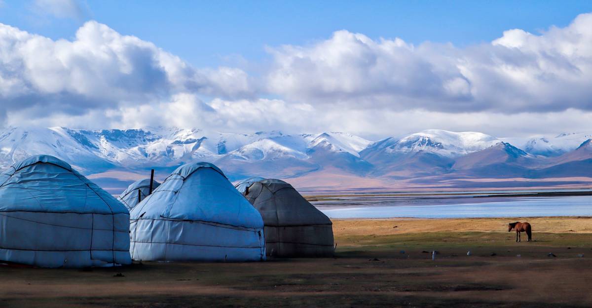 Traditional white yurts situated on the grassy plains near Lake Song Kul in Kyrgyzstan.