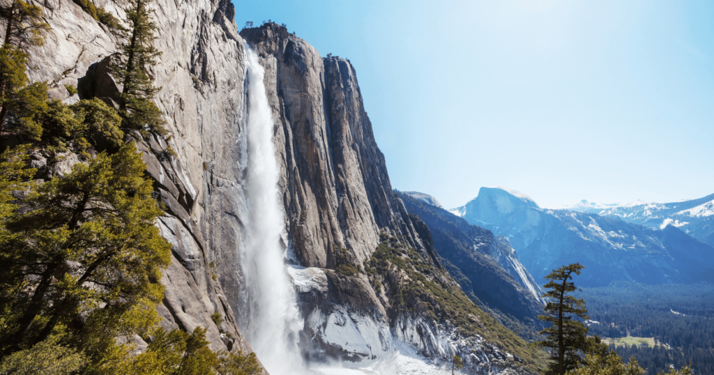 A view of Yosemite Falls and the famous granite cliffs under a blue sky.