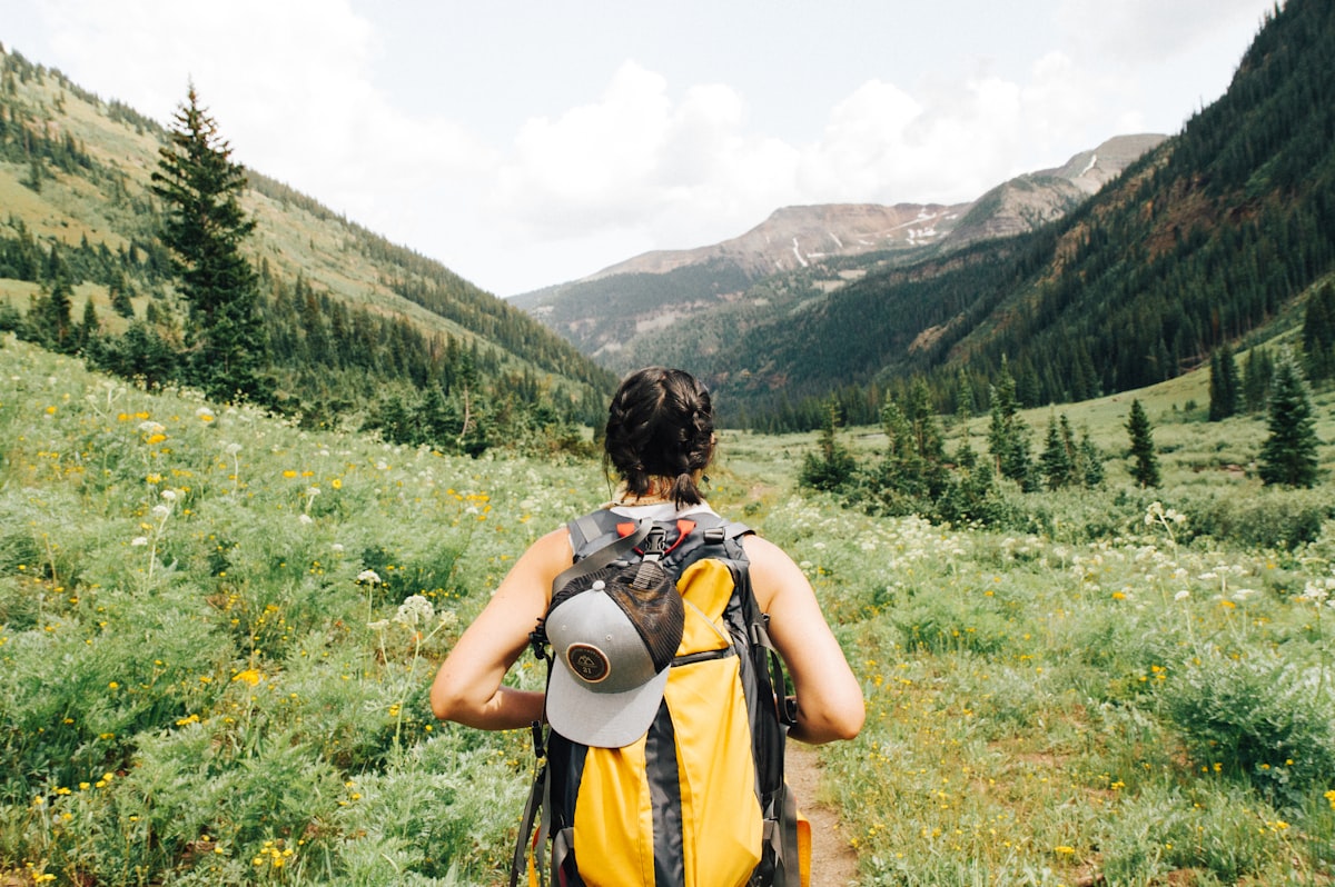 A young traveler with a backpack overlooking a mountain range.
