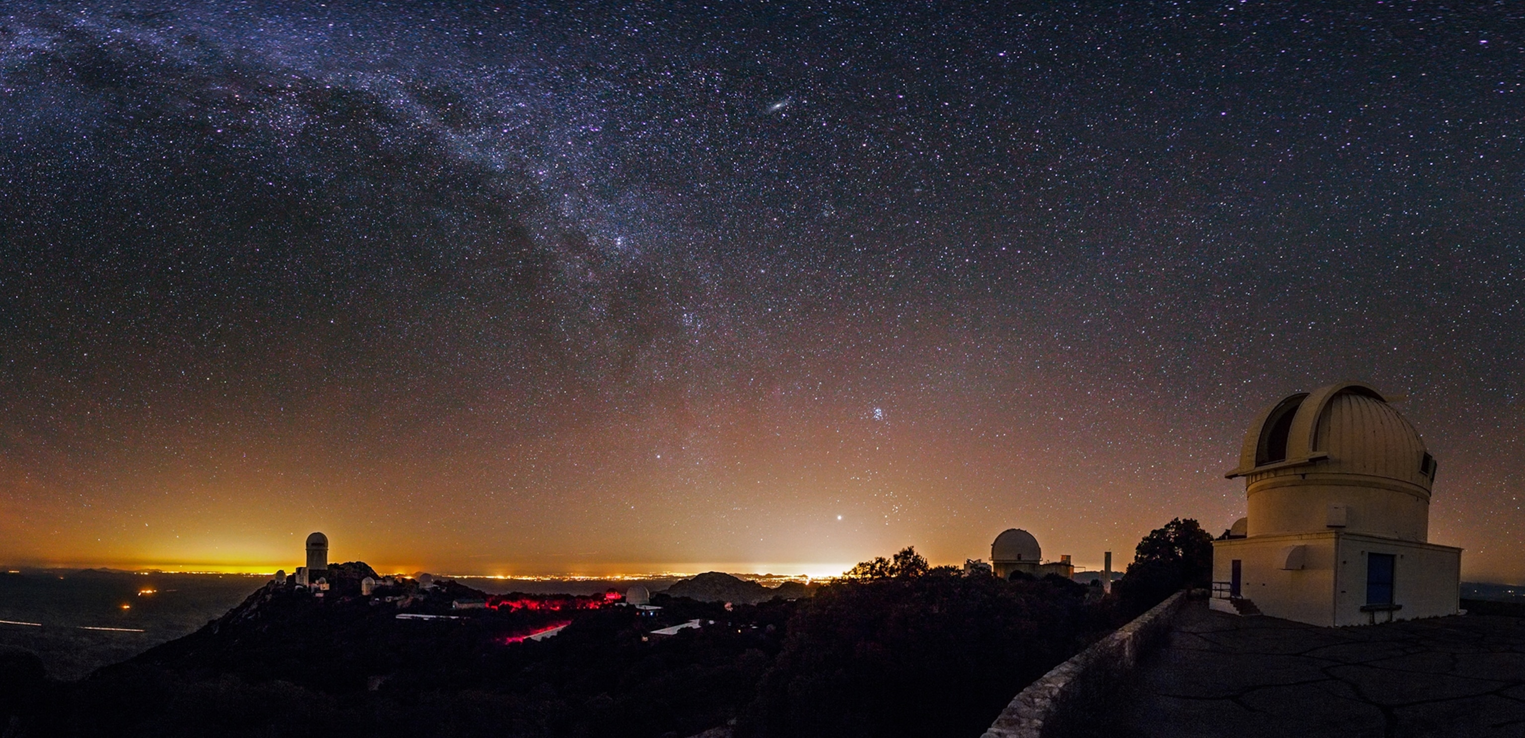 The WIYN 0.9 meter telescope at Kitt Peak silhouetted against a star-filled night sky.