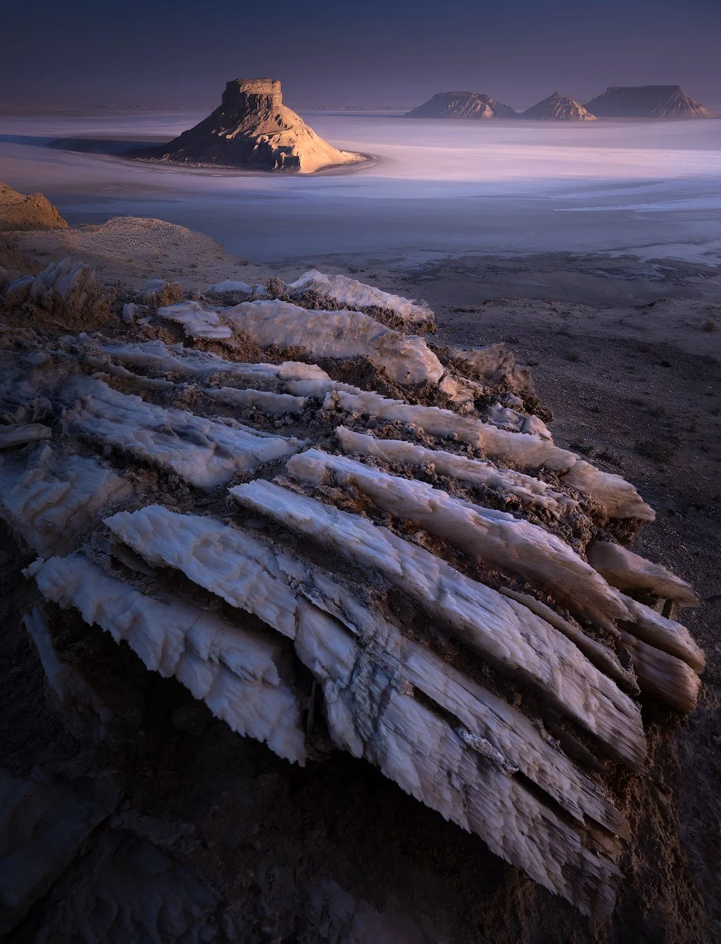 A salt lake with soft pink and blue pastel hues reflecting the sky in Mangystau.