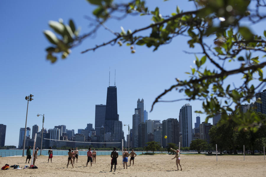 People playing beach volleyball at North Avenue Beach with the city skyline behind them.