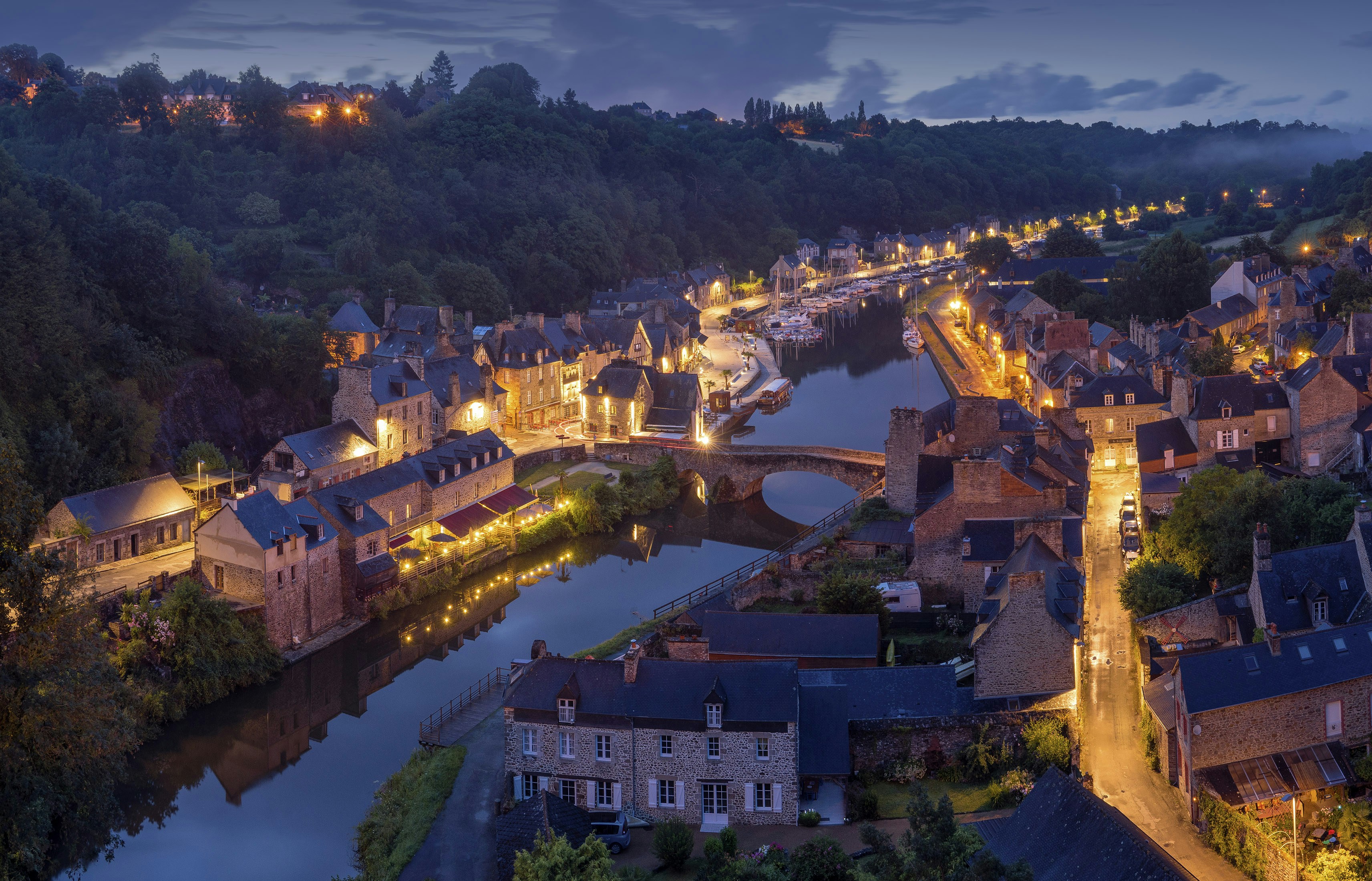 Medieval brick buildings lining a quiet canal with a stone bridge.