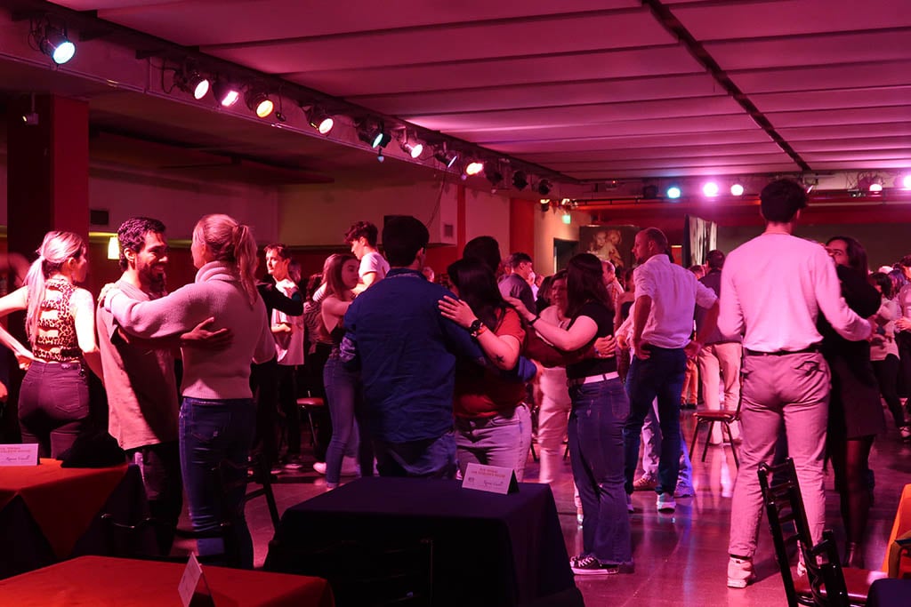 Local residents dancing tango in a dim, atmospheric milonga venue in the Almagro neighborhood.